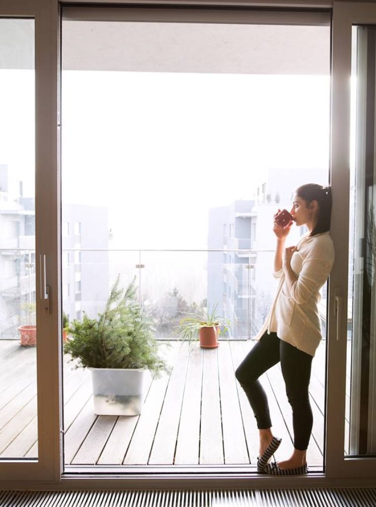 una-mujer-apoyada-en-las-puertas-de-aluminio-de-su-terraza_b8f6341f_900x900